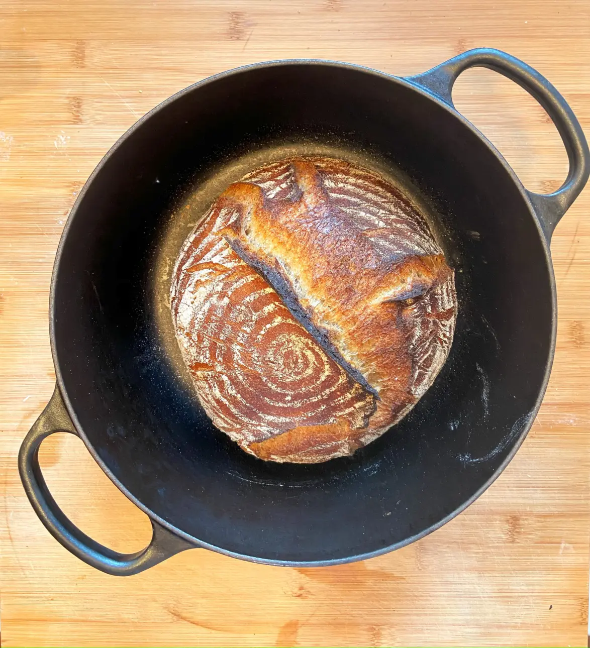 Ein frisch gebackenes Sauerteigbrot in einem gusseisernen Topf.