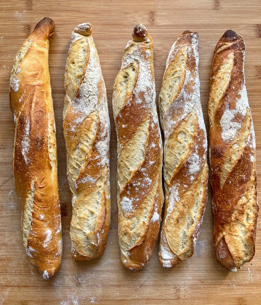 Fünf Baguette mit goldbrauner Kruste und leichtem Mehlüberzug.