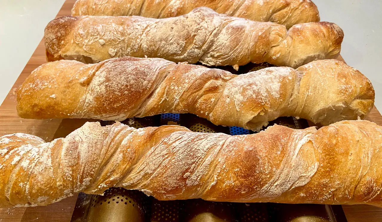 Ein Arrangement von drei frischen Brotstangen mit einer goldenen Kruste und einer leichten Bestäubung mit Mehl.